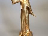 statue en or représentant une femme tenant un oiseau, posée sur un socle