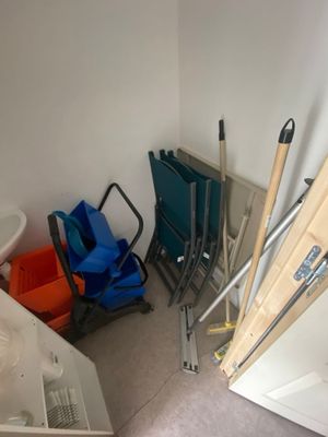 une pièce avec des toilettes, une chaise, une poubelle et une échelle