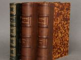 two old books sitting on top of each other on a table