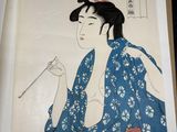 an image of a woman in a blue kimono is holding a cigarette