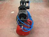 a red air compressor sitting on the floor in a warehouse