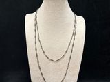 a white mannequin with a long chain on a black background
