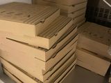 Plusieurs boîtes de pizza sont empilées les unes sur les autres dans une cuisine.