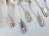 several silver spoons are lined up on a white surface