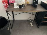 a desk with a coffee maker and a trash can on it