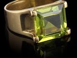 une image représentant une bague sertie d'une pierre verte sur un fond noir
