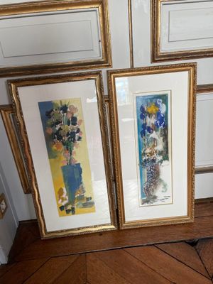 three framed pictures on the wall next to a vase of flowers