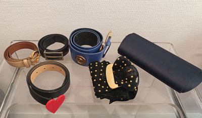many belts and other accessories sitting on a clear tray