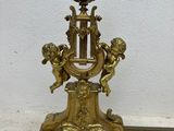 a gold clock on a stand with angels on it