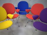 six chaises colorées disposées en cercle sur une surface blanche