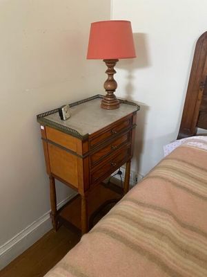 une petite table sur laquelle est posée une lampe, à côté d'un lit