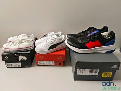 Plusieurs paires de chaussures sont posées sur des cartons, sur une table.