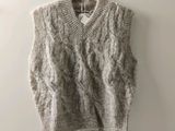 Le pull est suspendu à un cintre accroché au mur.