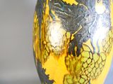 un vase jaune sur lequel est peint un oiseau noir