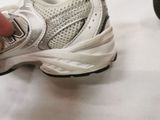 a person holding a pair of shoes on a white surface
