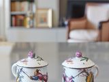 two cups sitting on a table in front of a bookshelf