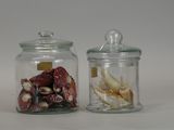 two glass jars with shells in them on a white surface