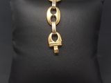 a black pillow with a gold chain bracelet on it
