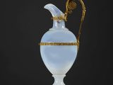 un vase ancien en verre, orné d'une bordure dorée et d'une anse, posé sur une table blanche