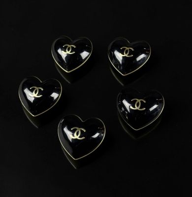 four heart shaped black and gold chandelier buttons on a black background