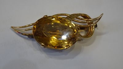 a close up of a brooch with a golden stone on it