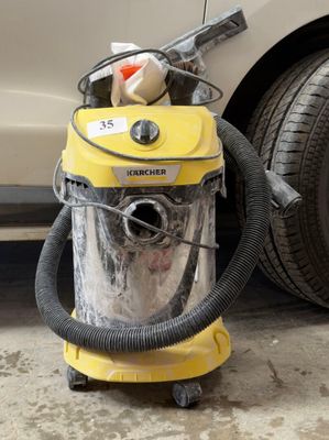 un aspirateur jaune posé par terre à côté d'une voiture
