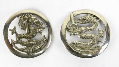 deux boutons métalliques ornés d'un dragon, sur un fond blanc