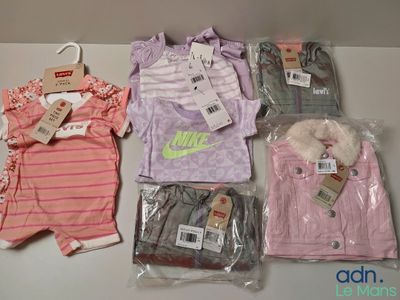 several baby clothes sitting on top of a table next to a hanger