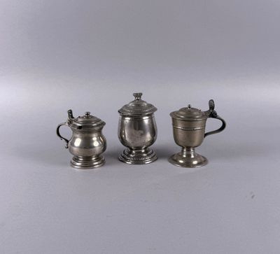 three silverplated teapots and a sugar shaker on a table