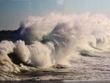 une photo montrant une grosse vague déferlant sur le rivage