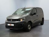 La camionnette grise est garée dans une grande pièce au sol noir.