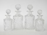 four clear glass bottles with decorative designs are lined up on a white surface