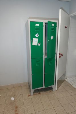 un casier vert dans une salle de bains avec des toilettes dans un coin