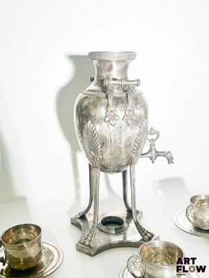un vase en argent posé sur une table, à côté d'autres plats en argent