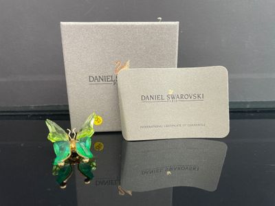 une image représentant une figurine de papillon verte et jaune posée à côté d'une boîte