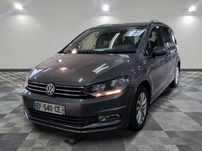 La Volkswagen Touran est garée dans une grande pièce au sol carrelé en damier.