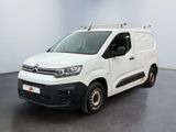 La camionnette blanche est garée dans une pièce au sol noir.