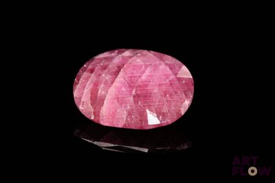 a close up of a pink stone on a black surface