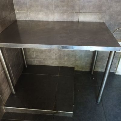 a stainless steel table in the corner of a bathroom