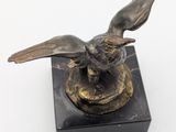 statue of a bird on a marble base on a white surface