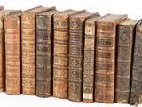 several old books are lined up in a row on a white surface