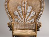 une chaise en osier ancienne sur laquelle est posé un coussin beige
