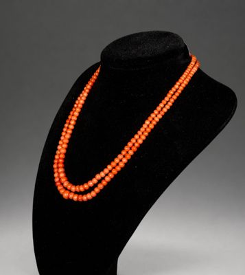 Un collier de perles orange est présenté sur un mannequin noir
