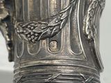a close up of a silver vase with a bird on it