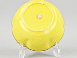 a yellow plate sitting on a stand on a gray surface