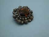 a close up of a silver broochle with a brown stone in it