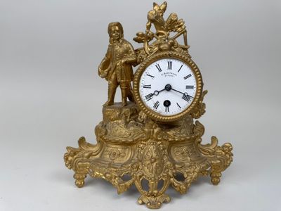 a gold clock with a statue on top of it