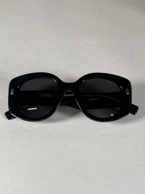 une paire de lunettes de soleil noires posée sur une table blanche