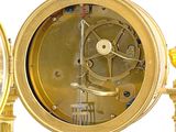 a gold clock that is sitting on a stand