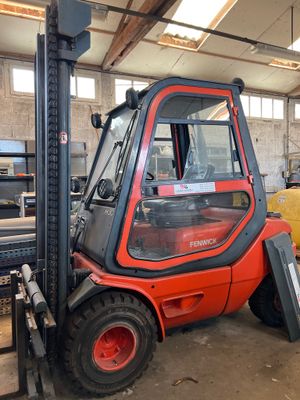 a forklift in a warehouse with a yellow truck in the background